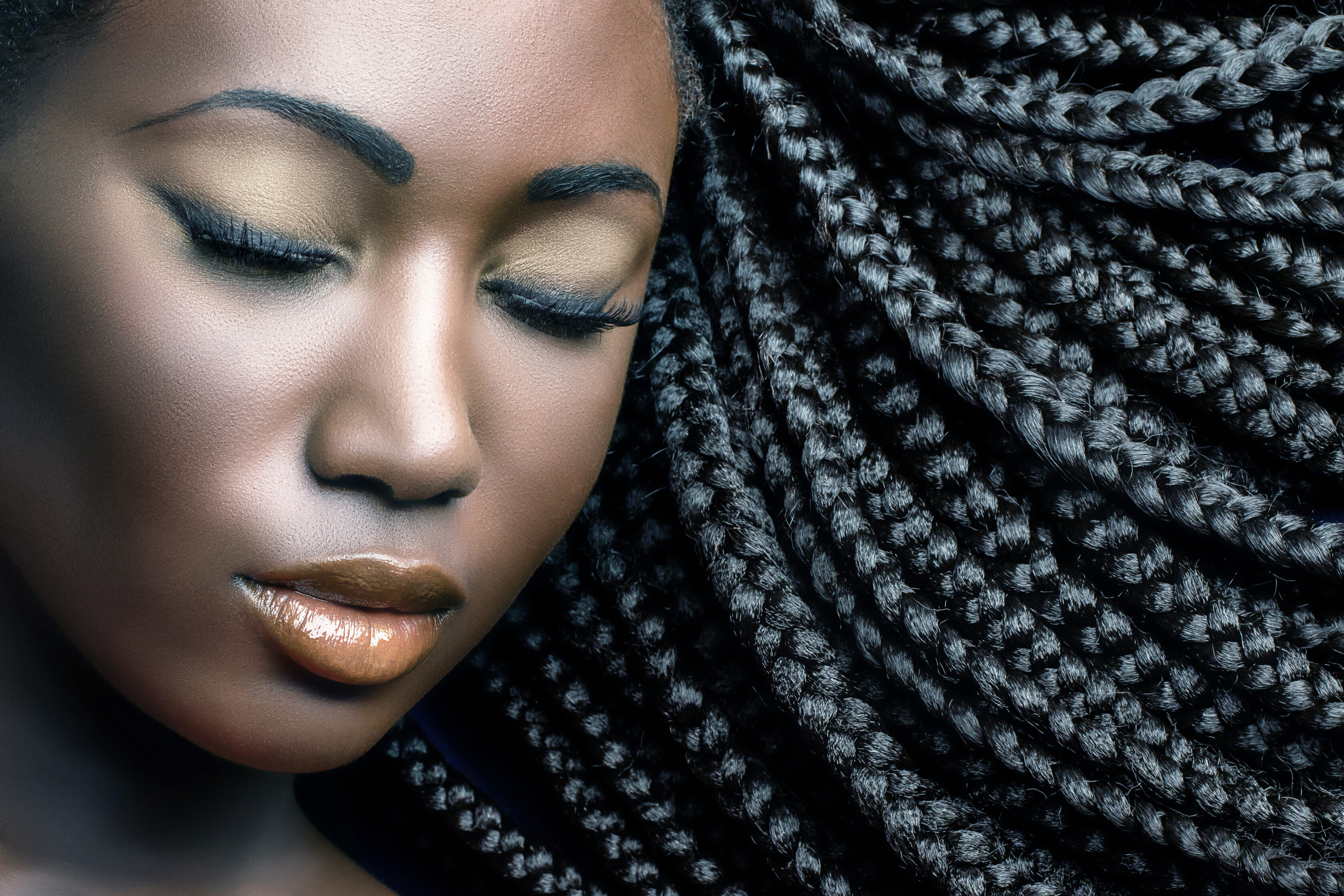 Extreme close up beauty cosmetic portrait of young african woman  with eyes closed.Girl wearing professional make up showing black braided hairstyle.